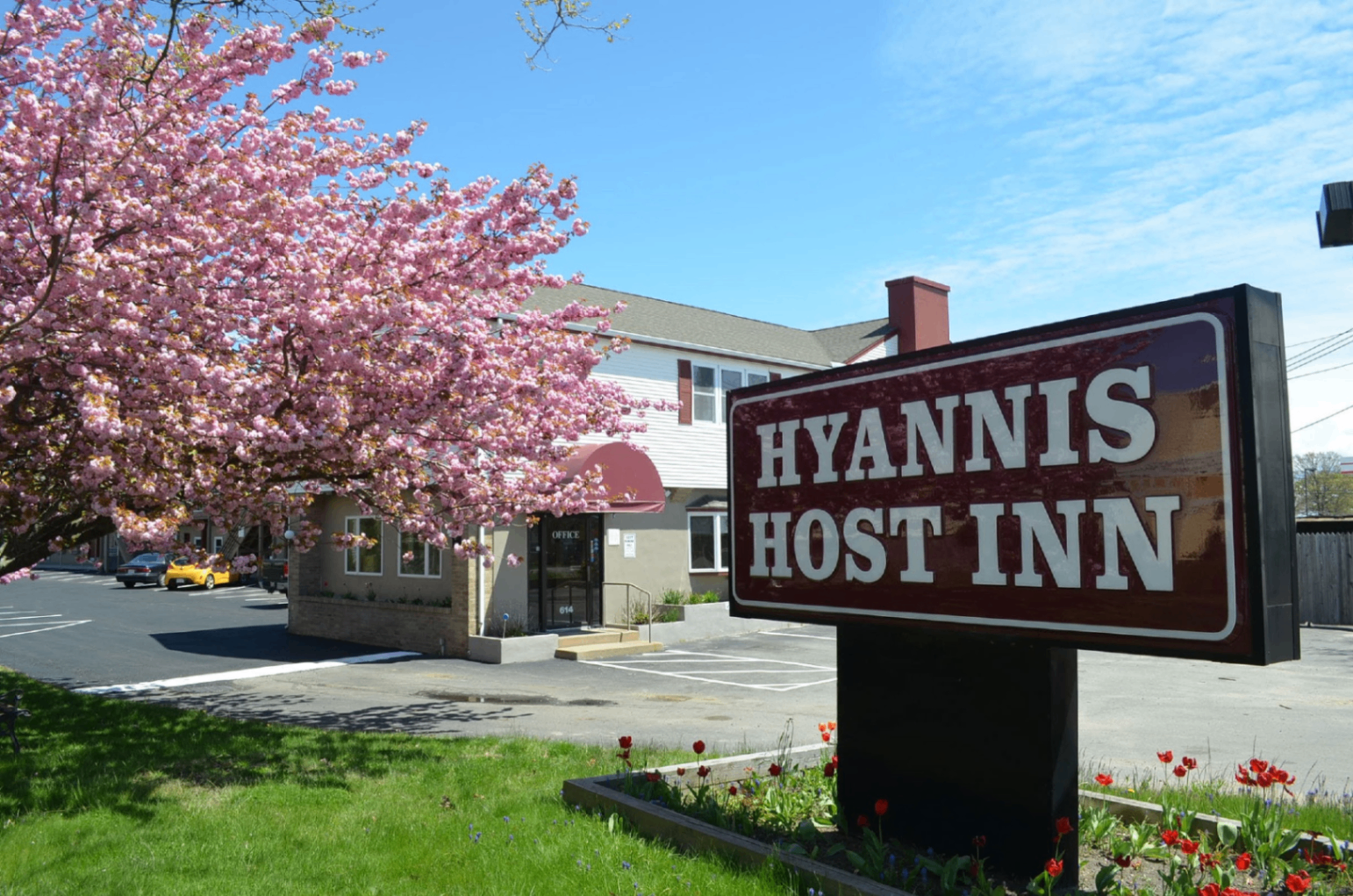 Hyannis Host Inn exterior framed by blooming spring trees